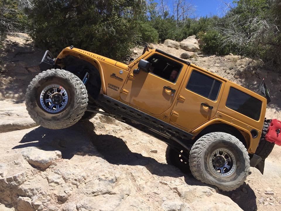 Amp'd Rubicon flexing a front tire off the rock on a steep climb